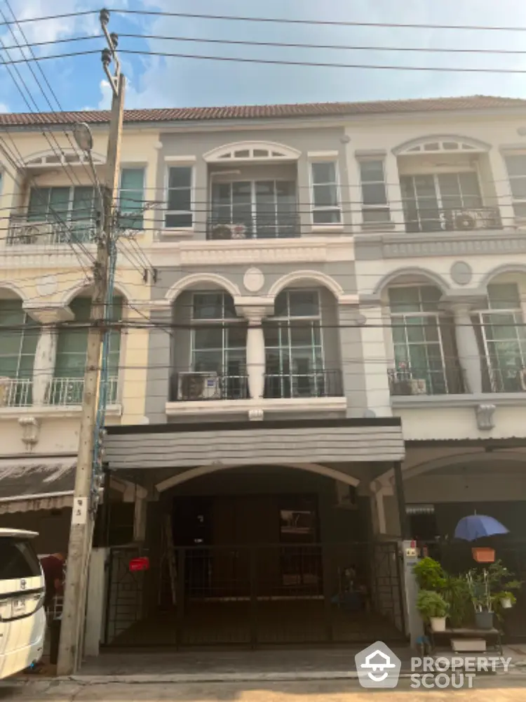 Charming townhouse facade with classic design elements, featuring arched windows and a secure carport, nestled in a vibrant neighborhood.