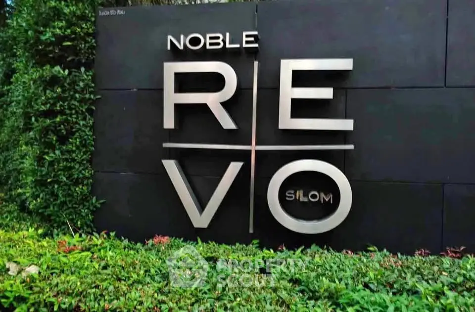 Modern real estate development sign with sleek design and lush greenery.