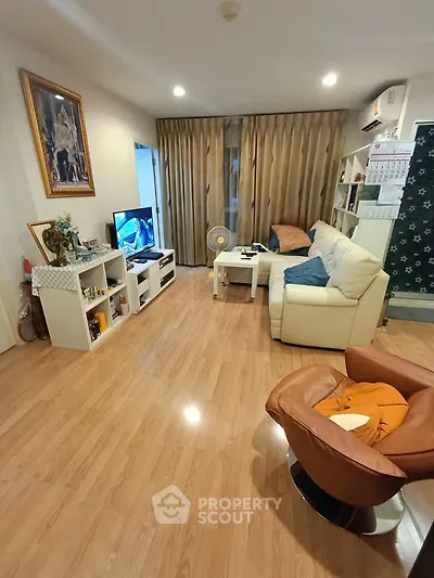 Spacious living room with modern decor and wooden flooring, featuring a cozy seating area and entertainment setup.