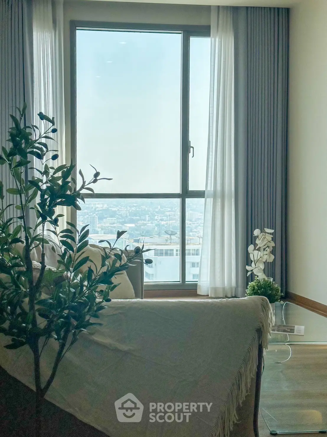Bright living room with large window offering stunning city view, cozy seating, and elegant decor.