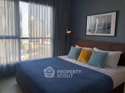 Stylish bedroom with city view, featuring modern decor and cozy bedding.