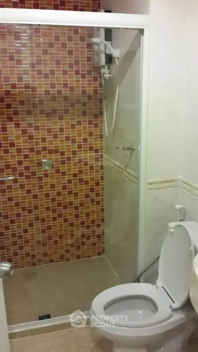 Compact bathroom with vibrant mosaic shower tiles and modern fixtures.