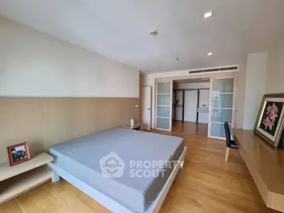 Spacious bedroom with modern decor and wooden flooring in a stylish apartment.