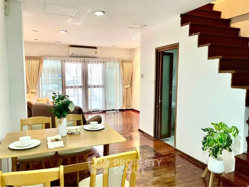 Charming duplex with wooden staircase and cozy dining area, perfect for modern living.