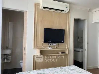 Modern bedroom with wall-mounted TV and air conditioning, featuring ensuite bathroom access.