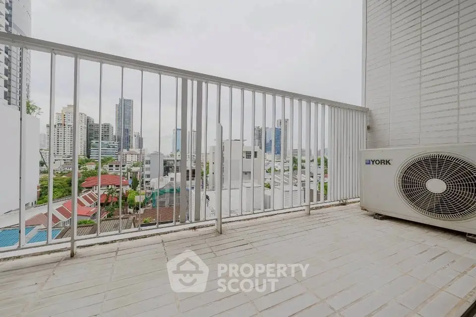 Spacious balcony with city view and air conditioning unit, perfect for relaxation.