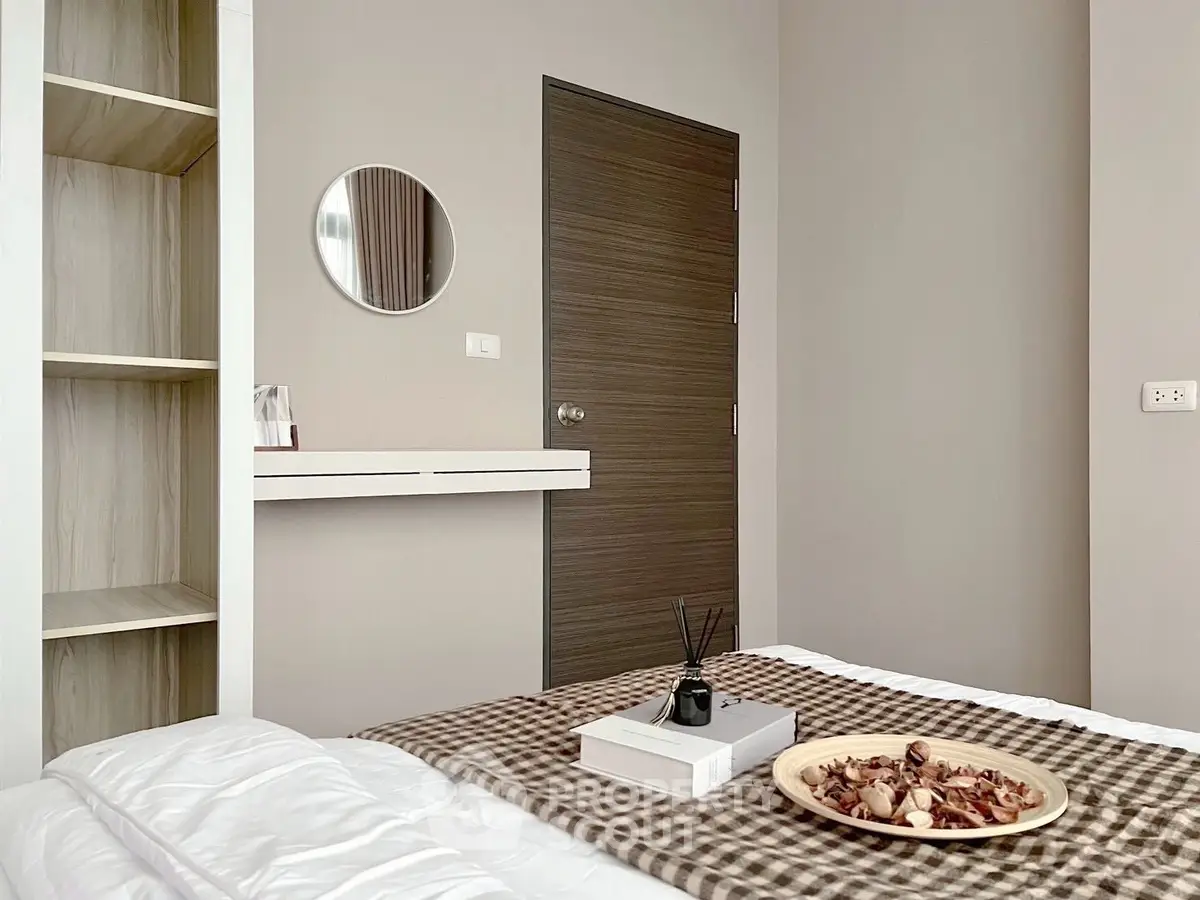 Modern bedroom with stylish decor and cozy ambiance, featuring a chic round mirror and elegant shelving.