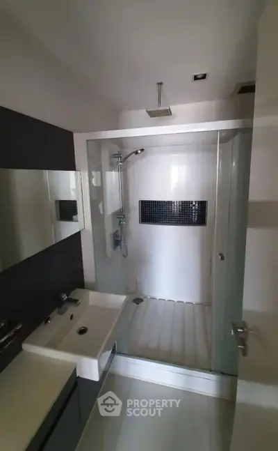 Modern bathroom with sleek shower and stylish sink in contemporary apartment.