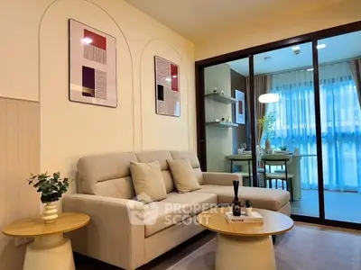 Modern living room with cozy sofa and stylish decor adjacent to dining area with glass partition.