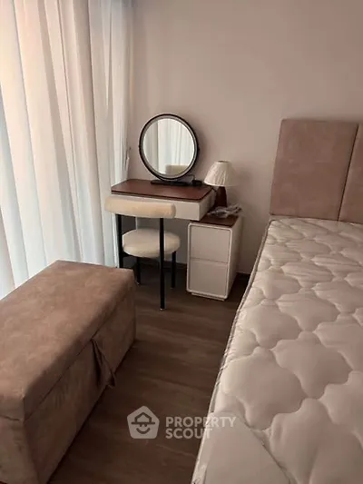Cozy bedroom with stylish vanity and plush seating, perfect for relaxation.