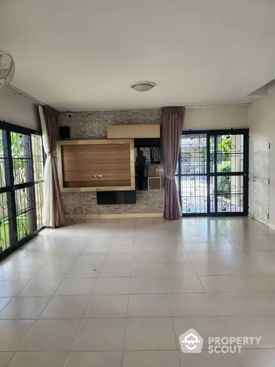 Spacious living room with large windows and tiled flooring