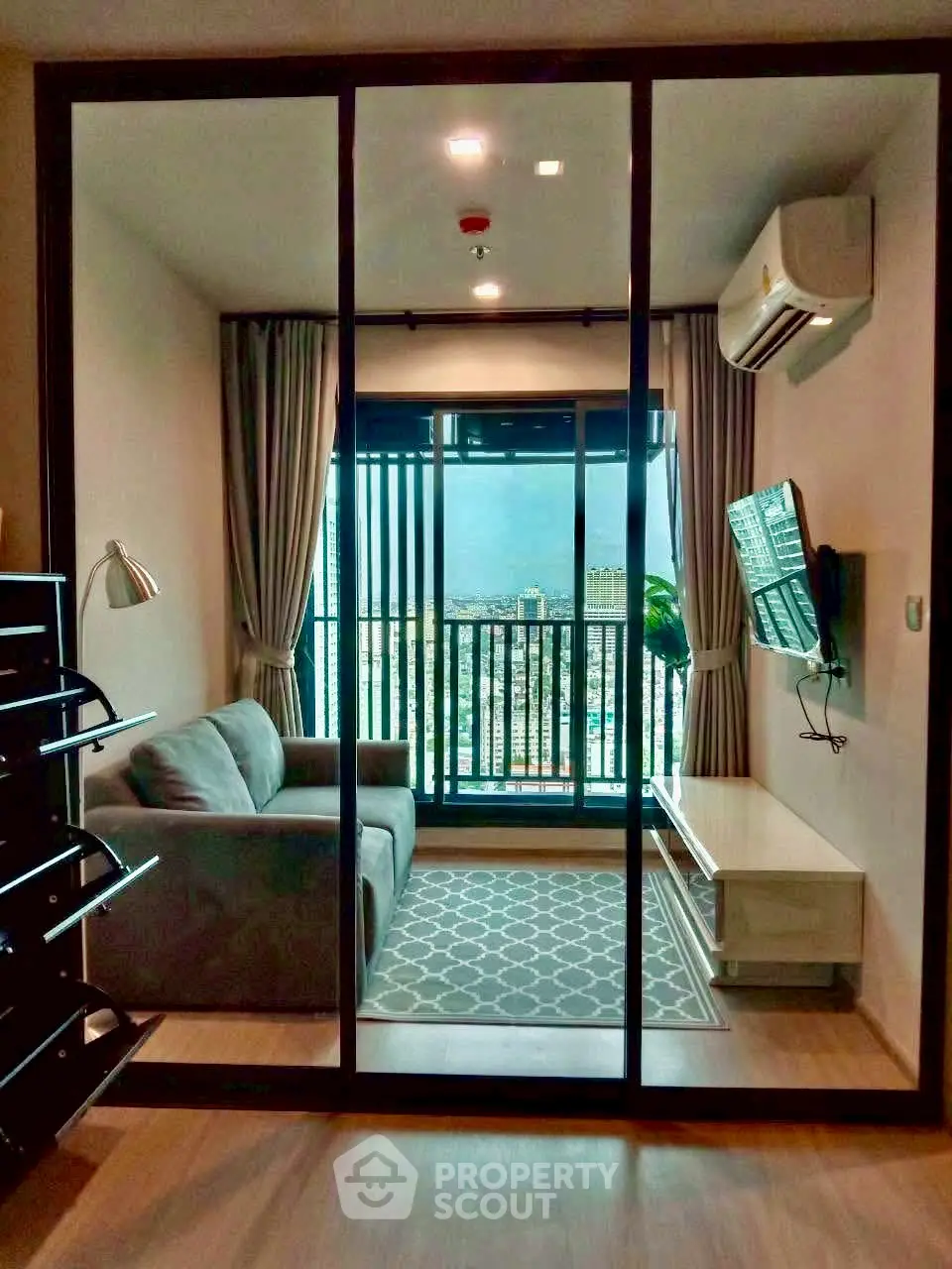 Modern living room with city view, cozy sofa, and wall-mounted TV in a stylish apartment.