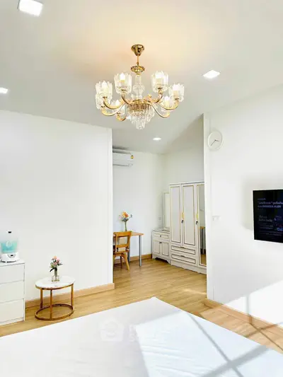 Elegant bedroom with chandelier and modern furnishings, featuring a cozy study nook.