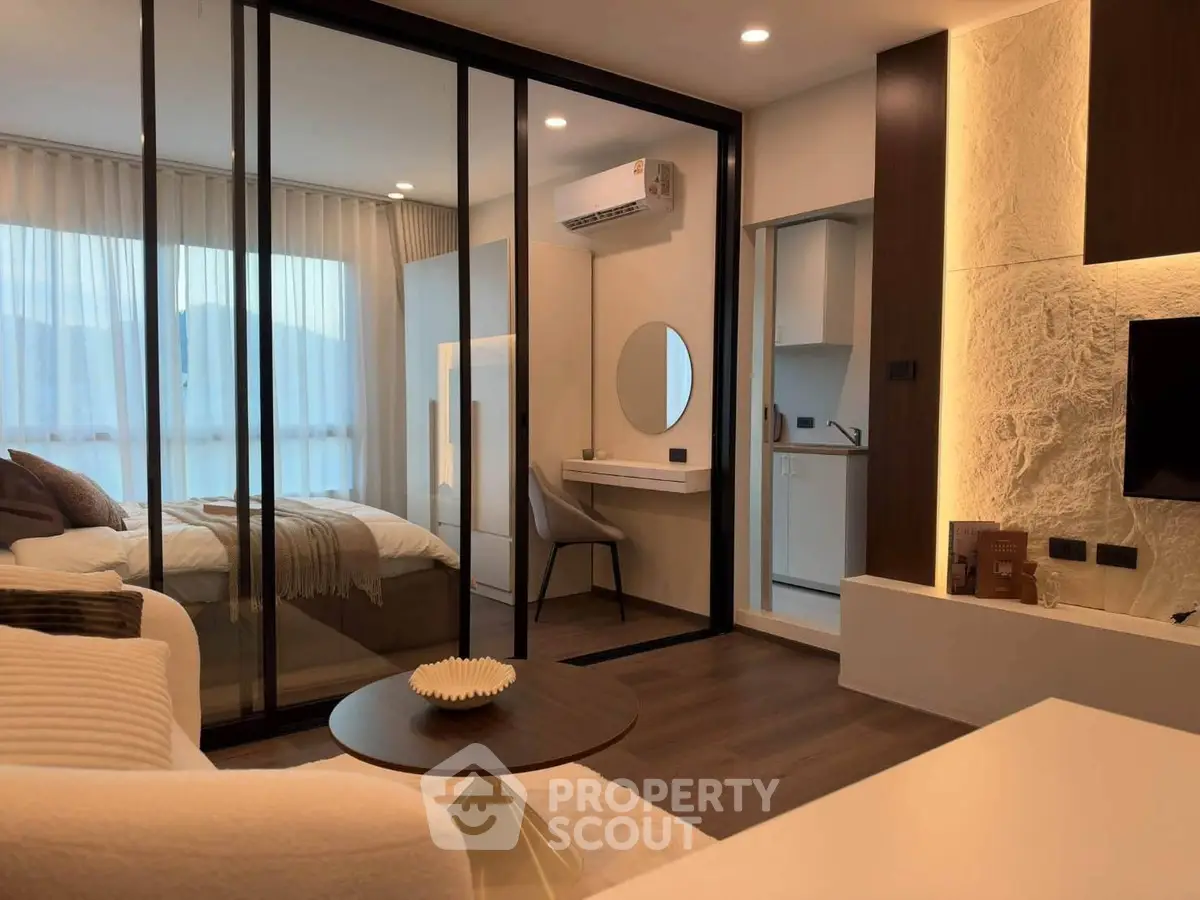 Modern studio apartment with glass partition, cozy living area, and stylish decor
