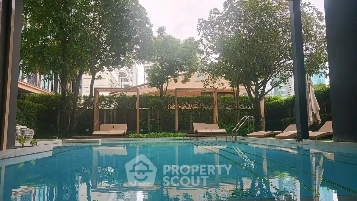 Luxurious outdoor pool area with lush greenery and elegant loungers, perfect for relaxation and leisure.