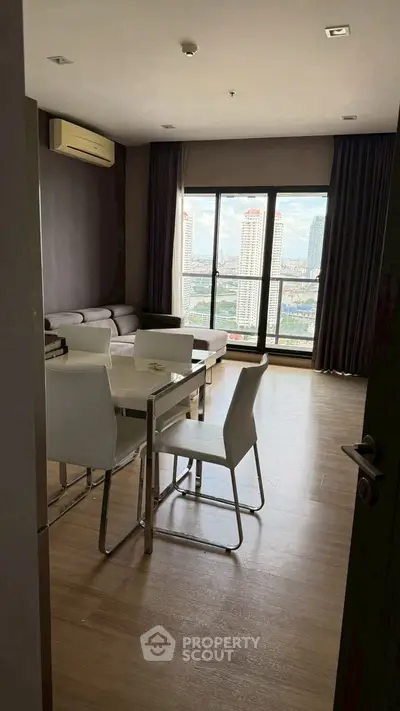 Modern living room with city view, featuring sleek furniture and large windows for natural light.
