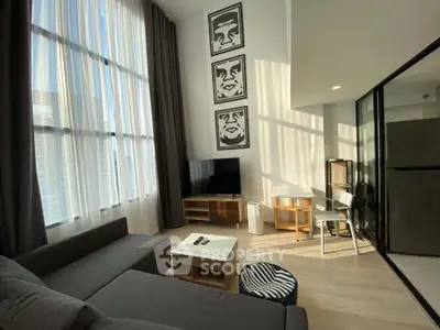 Modern living room with high ceilings, large windows, and stylish decor in a contemporary apartment.