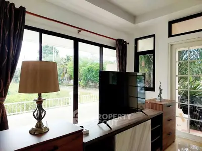Bright living room with large windows and garden view, featuring modern furniture.