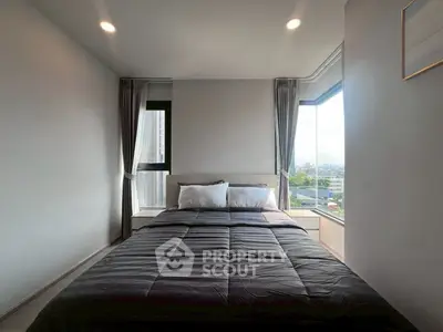 Modern bedroom with large windows and city view, featuring a cozy bed and elegant decor.