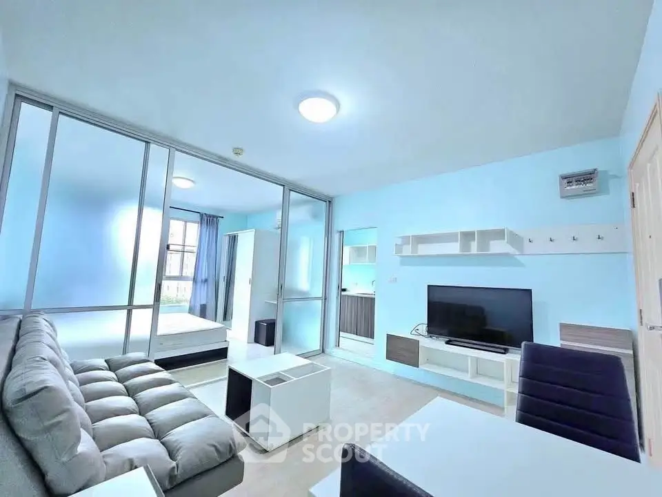 Modern living room with sleek furniture and bright blue walls, featuring a cozy sofa and flat-screen TV.
