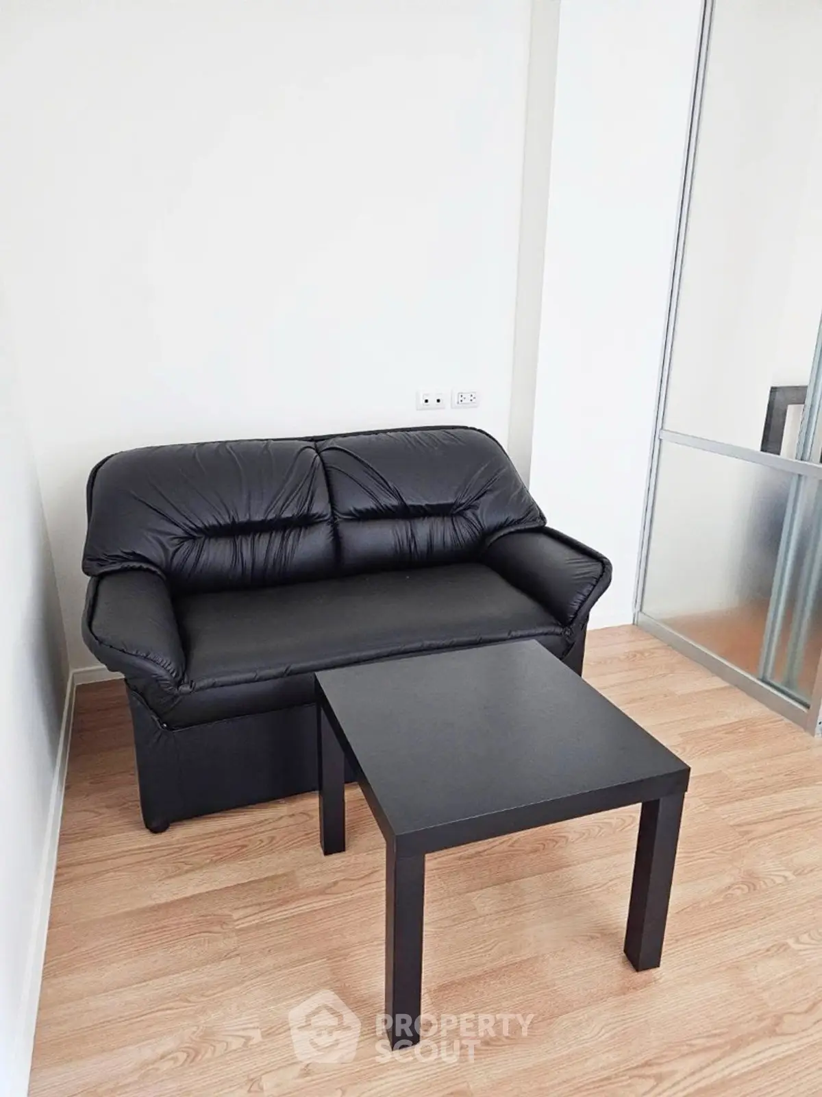 Cozy corner with black leather sofa and sleek table on wooden floor