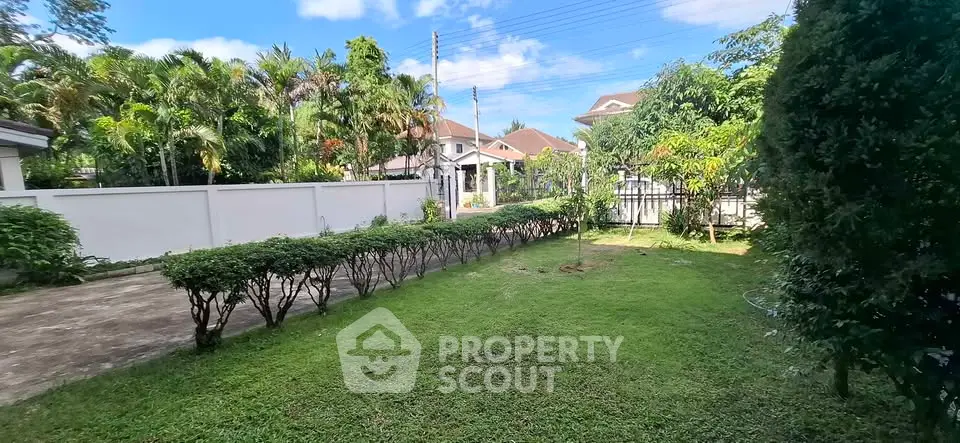 Spacious garden area with lush greenery and a view of neighboring houses, perfect for outdoor activities.