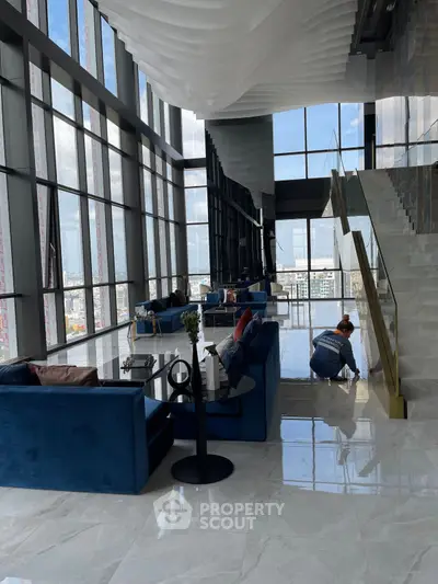 Luxurious modern living room with panoramic city views and elegant blue sofas.