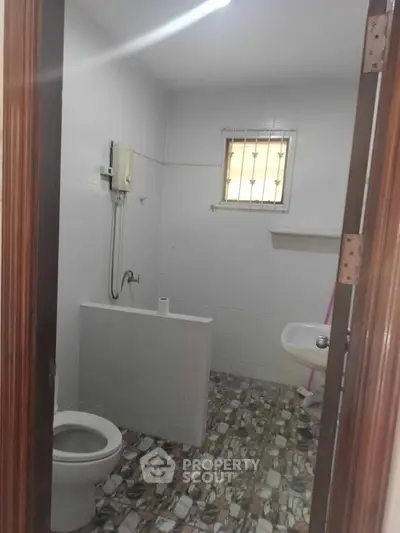 Compact bathroom with tiled floor and basic fixtures, ideal for small spaces.