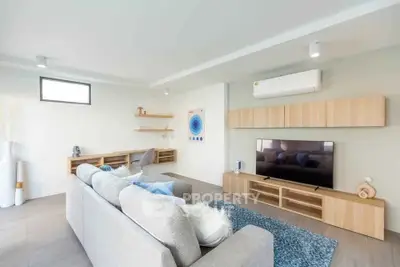 Modern living room with stylish furniture and wall-mounted TV, featuring a sleek air conditioning unit.
