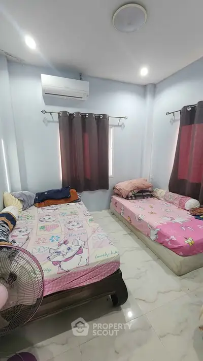 Cozy bedroom with twin beds, air conditioning, and natural light, ideal for comfortable living.