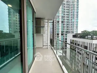 Spacious balcony with modern glass railing and city view in high-rise apartment