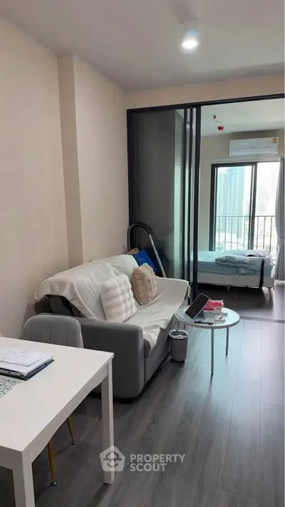 Modern living room with sliding glass doors leading to a cozy bedroom.