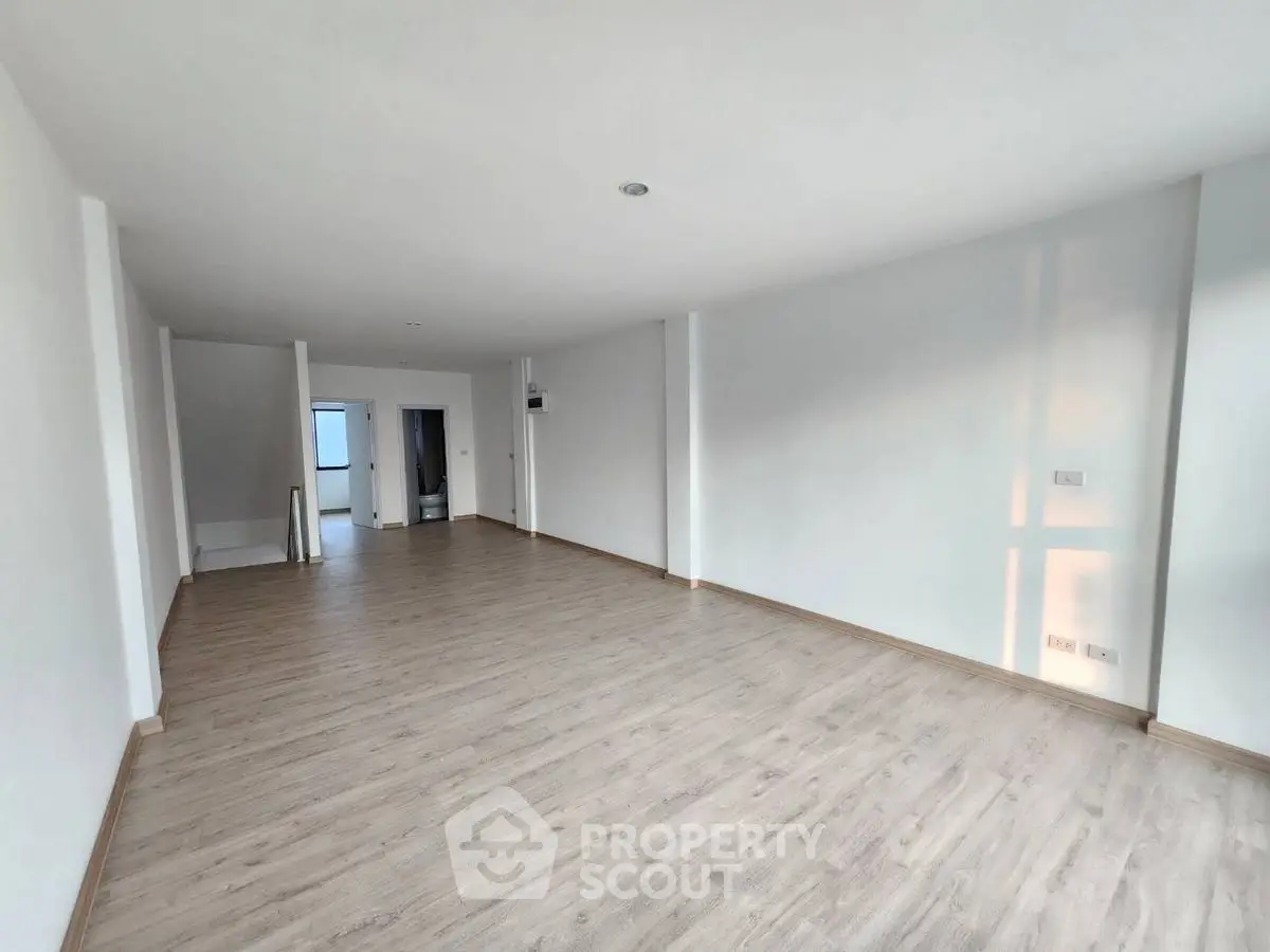 Spacious empty living room with wooden flooring and white walls