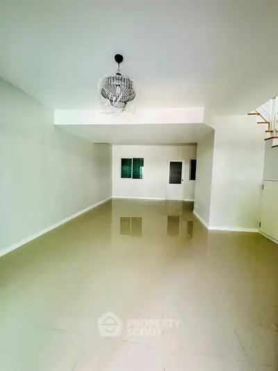Spacious empty room with modern chandelier and glossy tiled floor