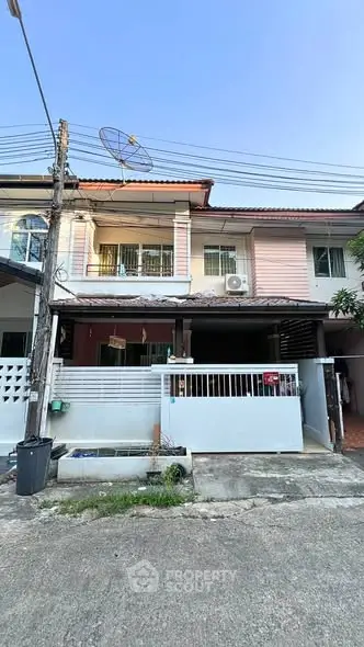 Charming two-story townhouse with satellite dish and gated entrance in a quiet neighborhood.