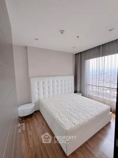Spacious bedroom with large window offering stunning city views, featuring a modern bed and elegant decor.