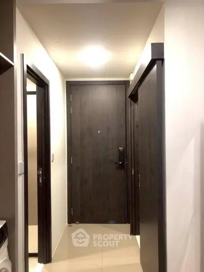 Modern apartment entrance with sleek dark wood doors and glossy tile flooring.