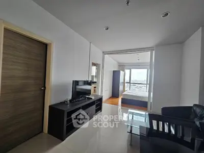 Modern apartment interior with sleek living room and bedroom view, featuring stylish furniture and large windows.
