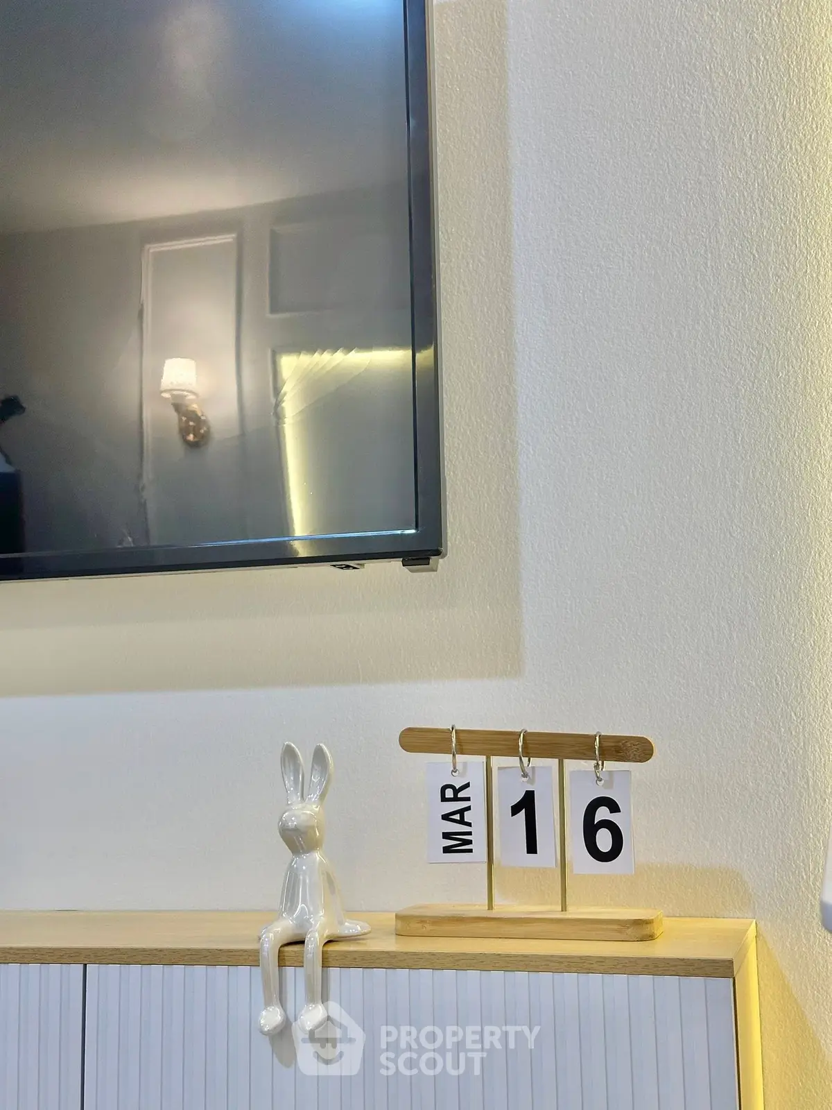 Modern interior with wall-mounted TV and decorative calendar on cabinet