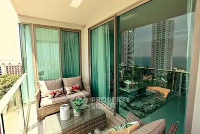 Luxurious balcony with stunning city and ocean views, featuring cozy seating and modern glass railings.