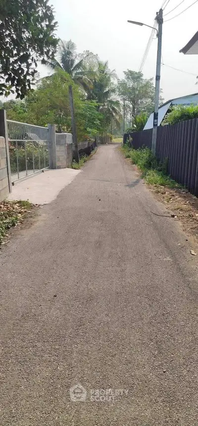 Charming rural pathway leading to a serene residential area, perfect for peaceful living.