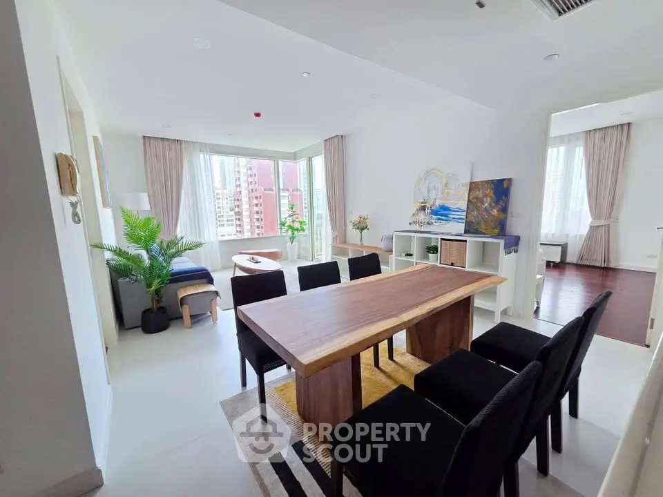 Spacious modern living room with elegant dining area and large windows offering city views.
