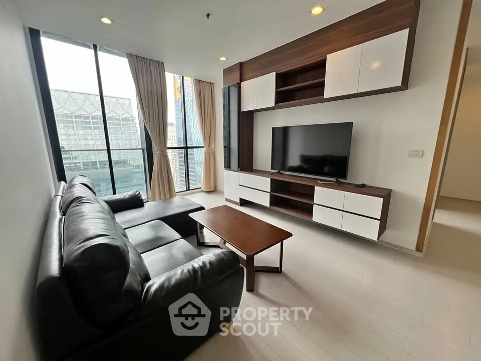 Modern living room with sleek furniture and large windows offering city views.