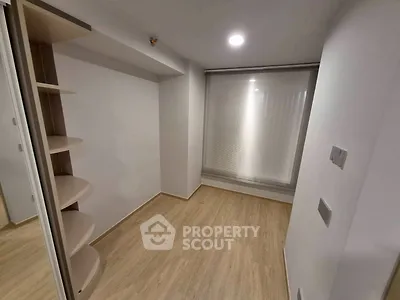 Minimalist small room with wooden flooring and built-in shelves, perfect for storage or study.