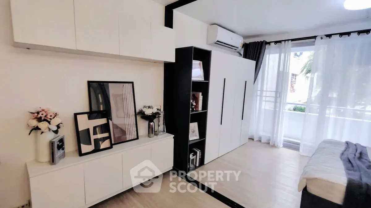 Modern bedroom with sleek storage and balcony view, featuring stylish decor and natural light.