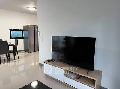 Modern living room with sleek TV unit and dining area in open layout.
