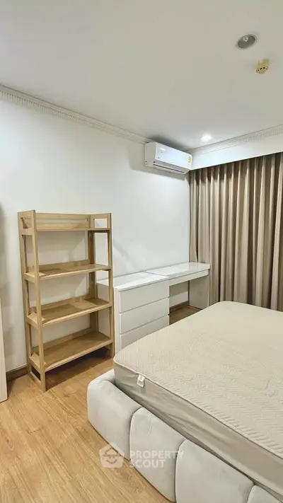 Modern bedroom with minimalist design, featuring a comfortable bed, wooden flooring, and ample natural light.