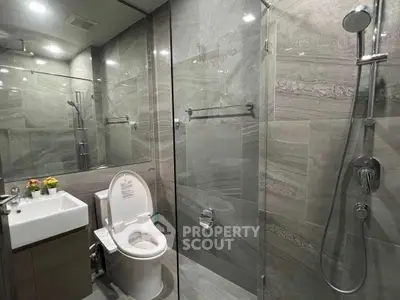 Modern bathroom with glass shower and sleek fixtures in luxury apartment.