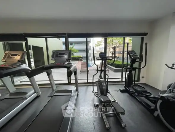 Modern gym with exercise equipment and large windows offering outdoor views.