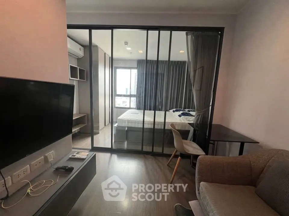 Modern apartment interior with glass partitioned bedroom and cozy living area.